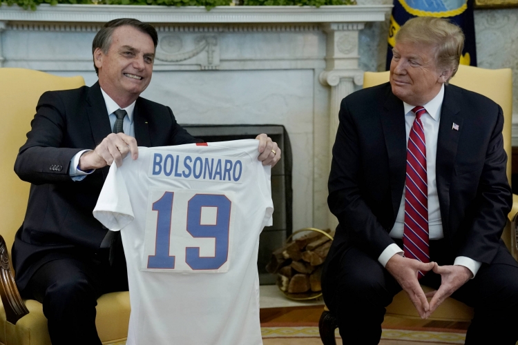 Jair Bolsonaro recebe uma camisa de time de futebol norte-americano de Donald Trump em Washington, Estados Unidos