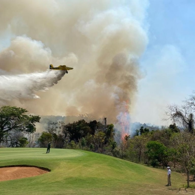 Aeronave joga água para ajudar no controle das chamas perto do condomínio Quinta do Golfe 